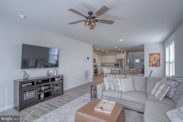 living room featuring ceiling fan and light hardwood / wood-style flooring