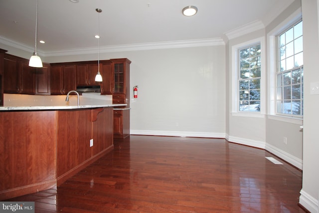 kitchen featuring ornamental molding, decorative light fixtures, a kitchen bar, dark hardwood / wood-style flooring, and sink