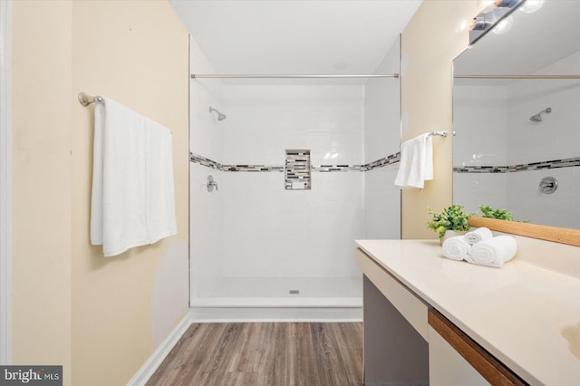 bathroom featuring vanity, a tile shower, and hardwood / wood-style floors