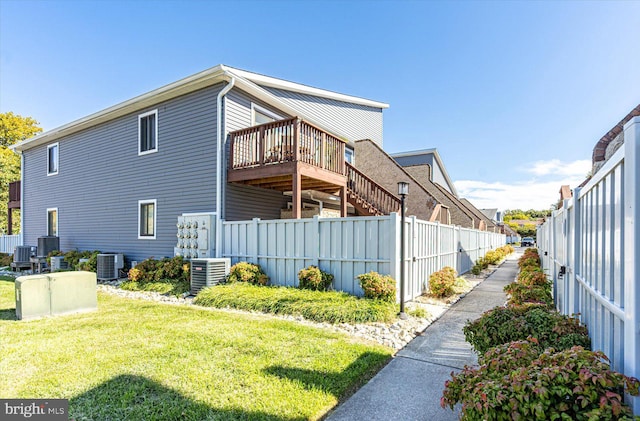 view of property exterior with cooling unit, a wooden deck, and a lawn