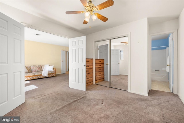 unfurnished bedroom with a closet, ensuite bath, light colored carpet, and ceiling fan