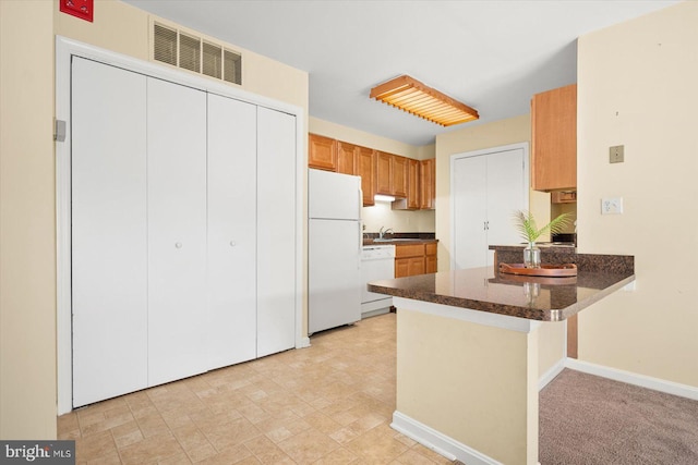 kitchen with sink, kitchen peninsula, light colored carpet, and white appliances