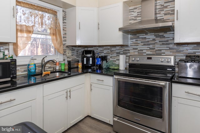 kitchen with stainless steel appliances, wall chimney range hood, and white cabinets