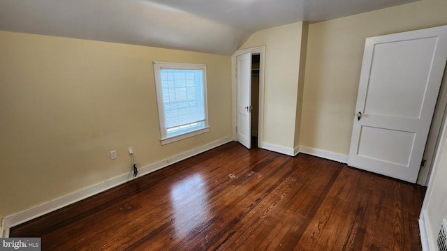 unfurnished bedroom with dark wood-type flooring and vaulted ceiling