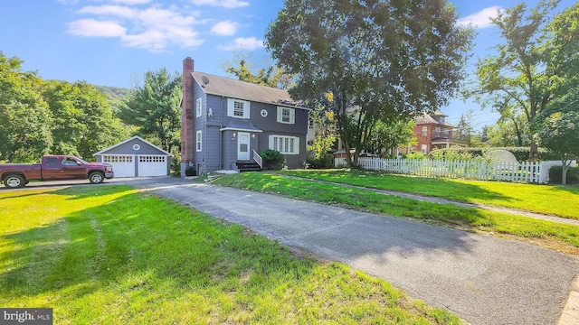 colonial house featuring a garage, an outdoor structure, and a front yard