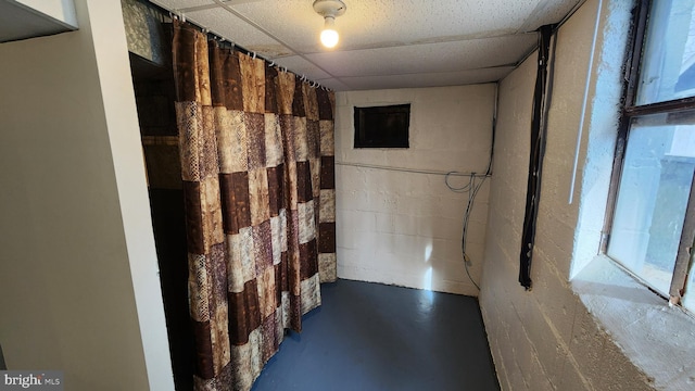 bathroom with a paneled ceiling and concrete floors