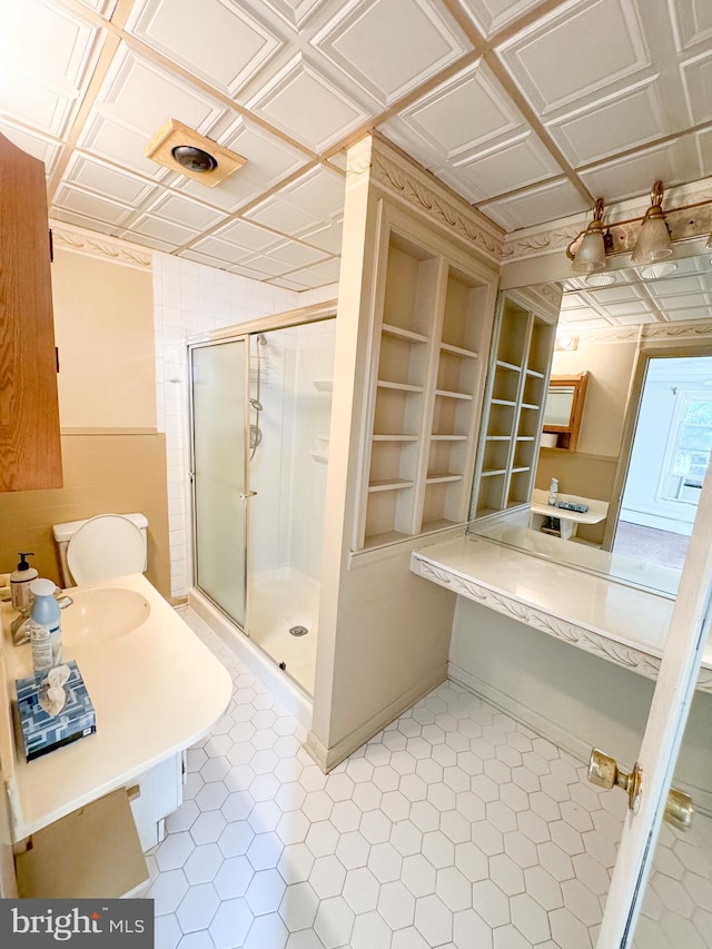 bathroom with sink, built in shelves, toilet, and an enclosed shower