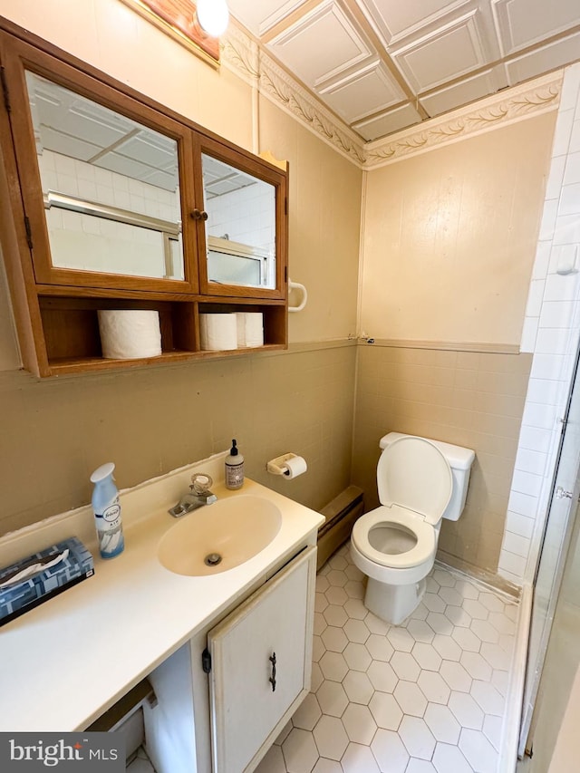 bathroom with tile patterned floors, toilet, a baseboard radiator, vanity, and tile walls