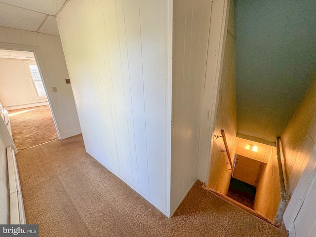 corridor featuring light carpet and wood walls