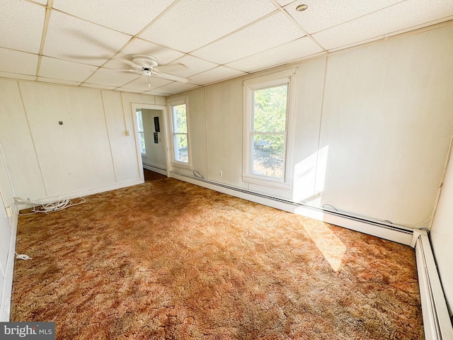 empty room with a paneled ceiling, carpet floors, a baseboard radiator, and ceiling fan