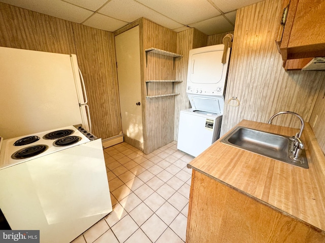 kitchen featuring a drop ceiling, stacked washer and dryer, sink, and light tile patterned floors