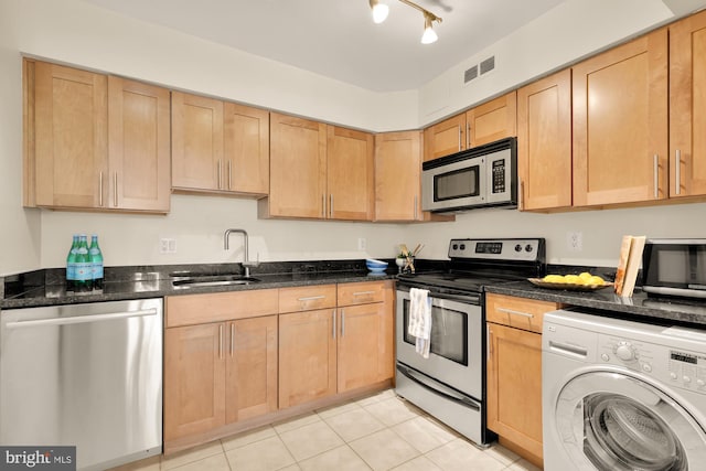 kitchen with dark stone countertops, sink, stainless steel appliances, washer / clothes dryer, and light tile patterned floors