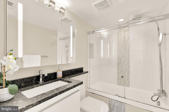 full bathroom featuring enclosed tub / shower combo, vanity, and toilet