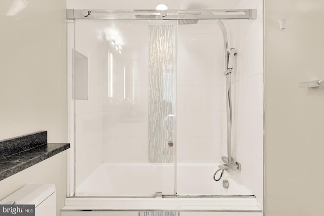 bathroom with bath / shower combo with glass door and toilet