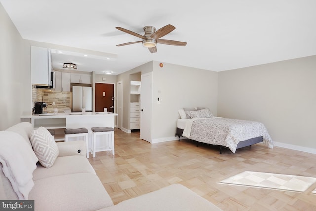 bedroom with light parquet flooring, white fridge, and ceiling fan