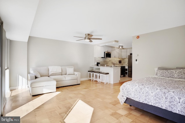 bedroom with light parquet floors, ceiling fan, and stainless steel refrigerator