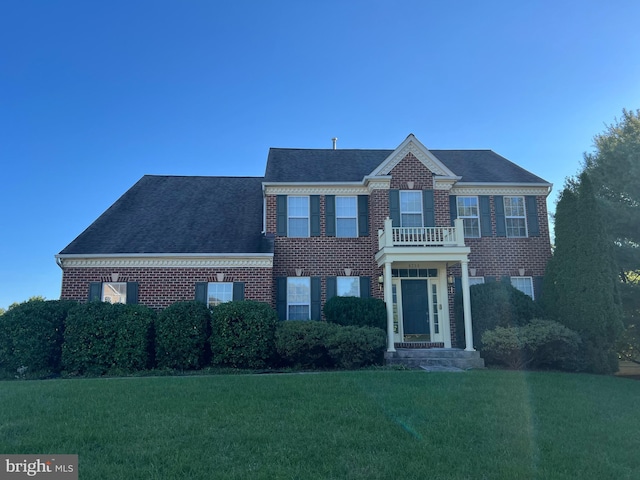 view of front facade with a balcony and a front yard