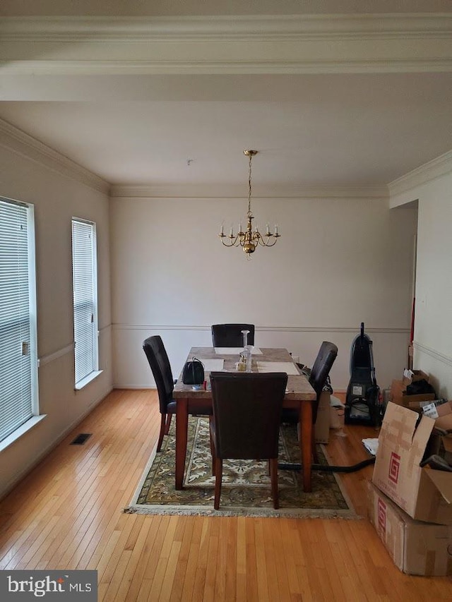 dining room featuring a notable chandelier, light wood-type flooring, and crown molding