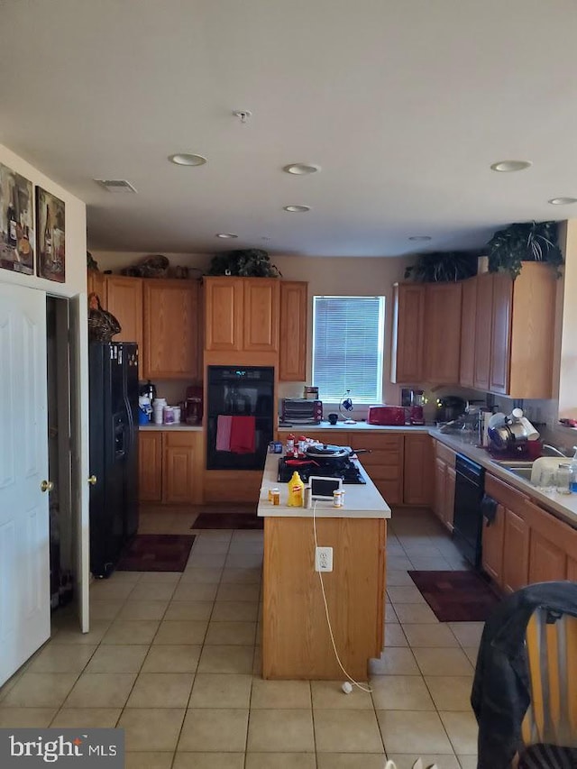 kitchen with light tile patterned floors, sink, a kitchen island, and black appliances