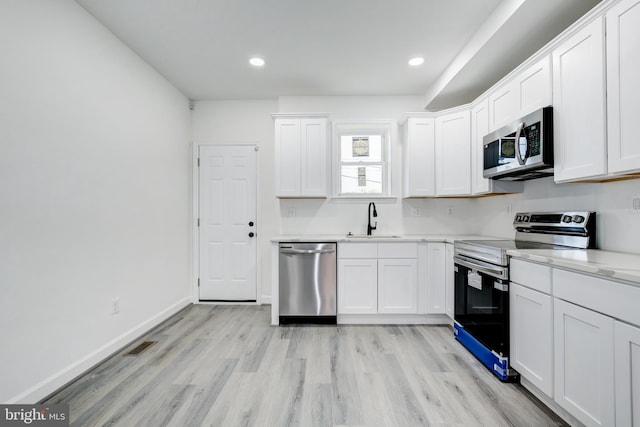 kitchen featuring white cabinets, appliances with stainless steel finishes, light hardwood / wood-style flooring, and sink