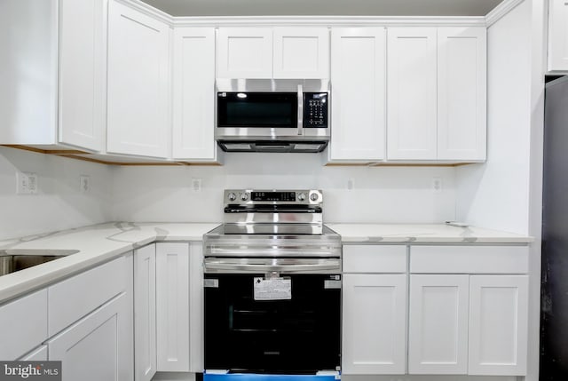 kitchen featuring white cabinets, appliances with stainless steel finishes, and light stone countertops