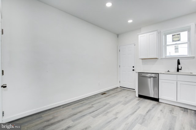 kitchen with light wood-type flooring, white cabinetry, stainless steel dishwasher, and sink