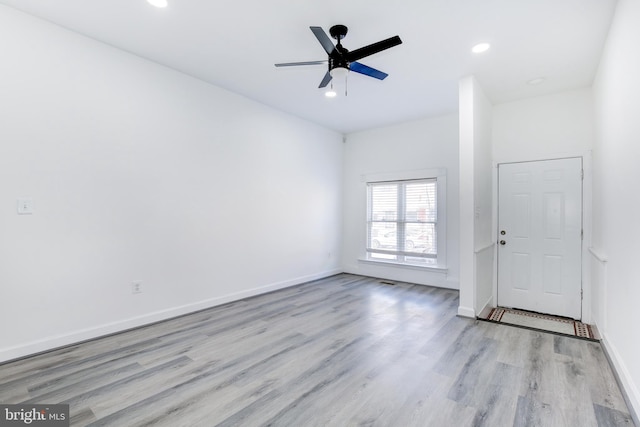 empty room with ceiling fan and light hardwood / wood-style flooring