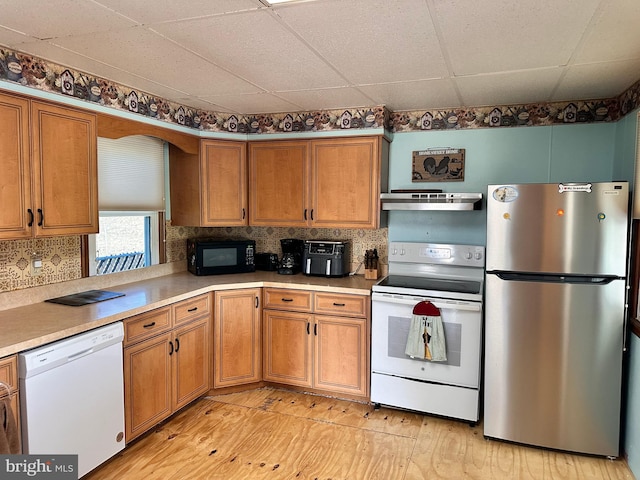 kitchen with a paneled ceiling, extractor fan, white appliances, and light wood-type flooring