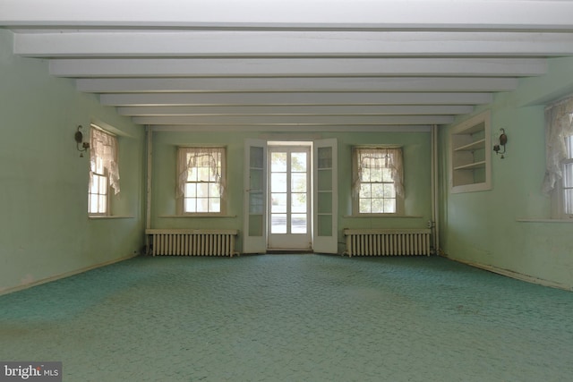 unfurnished room with radiator heating unit, beam ceiling, and a wealth of natural light