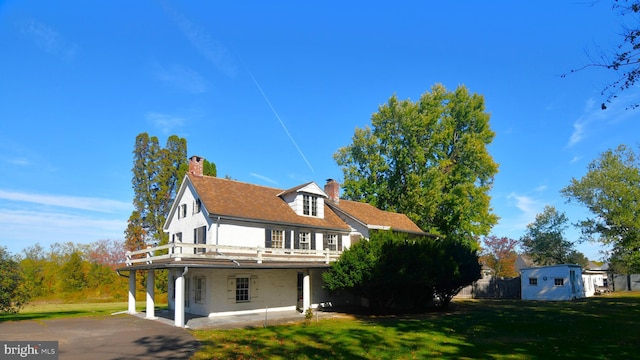 rear view of house with a balcony and a lawn