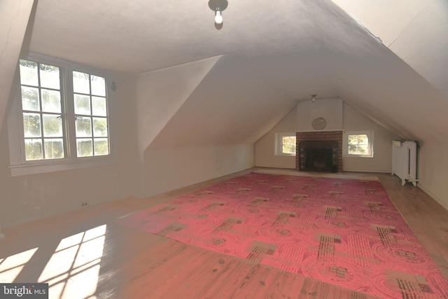 bonus room with a fireplace, vaulted ceiling, and hardwood / wood-style floors