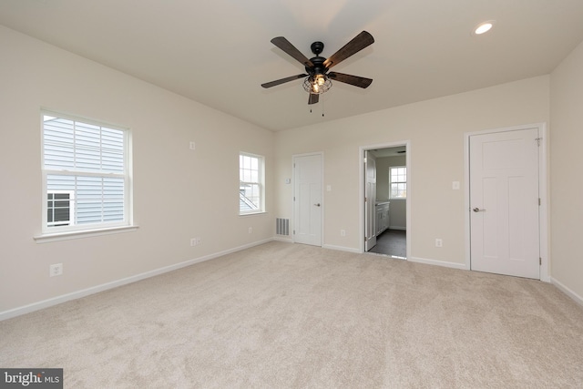 unfurnished bedroom with ensuite bath, ceiling fan, and light colored carpet