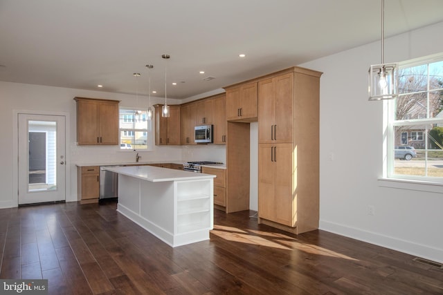 kitchen with a wealth of natural light, stainless steel appliances, dark wood-type flooring, and a kitchen island