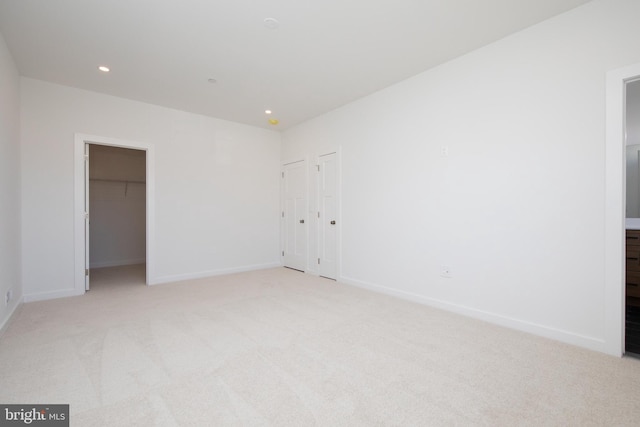 unfurnished bedroom with light carpet and a spacious closet