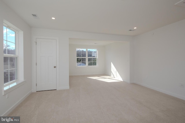 unfurnished room with light colored carpet and a healthy amount of sunlight