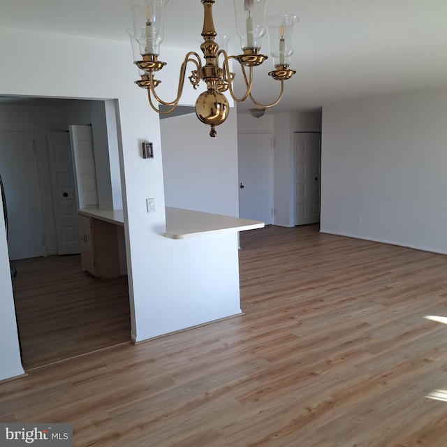 kitchen featuring kitchen peninsula, light hardwood / wood-style flooring, and hanging light fixtures