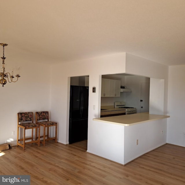 kitchen featuring kitchen peninsula, black fridge, white range with gas stovetop, and wood-type flooring