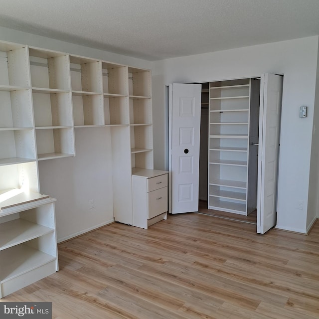 unfurnished bedroom with a textured ceiling, light hardwood / wood-style flooring, and a closet