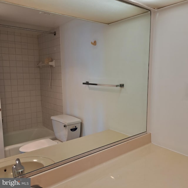 full bathroom featuring sink, tiled shower / bath, and toilet