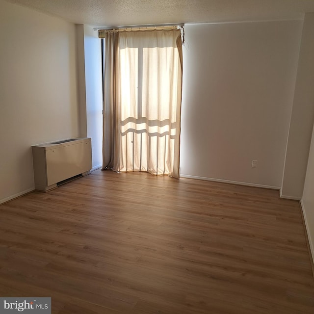 unfurnished room featuring wood-type flooring and a textured ceiling