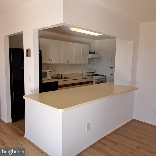 kitchen featuring kitchen peninsula, exhaust hood, white appliances, and light wood-type flooring