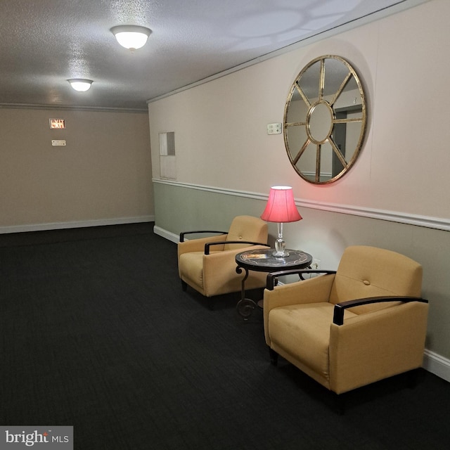 living area with carpet flooring, ornamental molding, and a textured ceiling