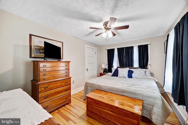 bedroom with ceiling fan, a textured ceiling, and light wood-type flooring