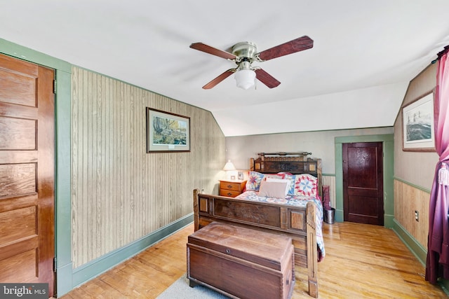 bedroom with ceiling fan, light hardwood / wood-style floors, and vaulted ceiling