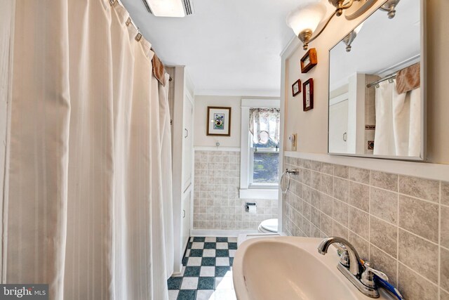 bathroom with toilet, sink, tile walls, and crown molding