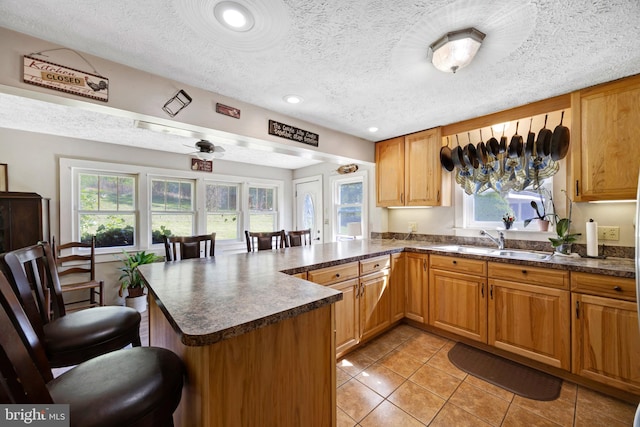 kitchen with a textured ceiling, kitchen peninsula, and sink