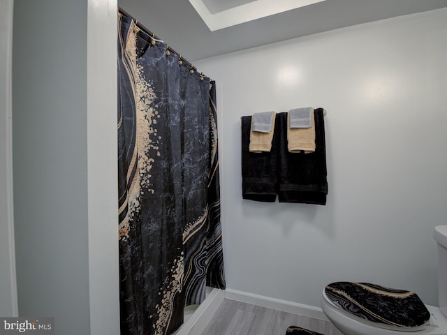 bathroom featuring a shower with curtain, hardwood / wood-style flooring, and toilet