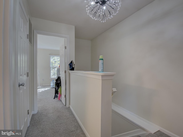 hall featuring light carpet and a notable chandelier