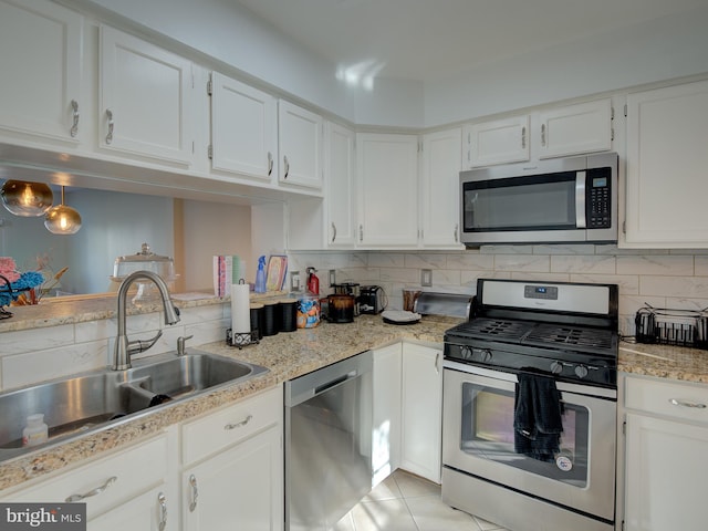 kitchen with appliances with stainless steel finishes, backsplash, sink, light tile patterned floors, and white cabinetry