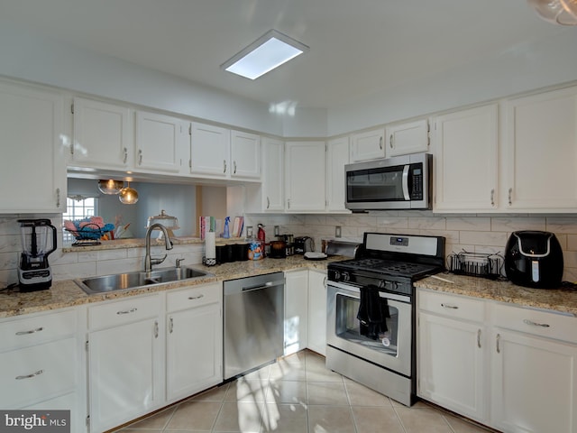 kitchen featuring white cabinetry, sink, decorative backsplash, light tile patterned floors, and appliances with stainless steel finishes